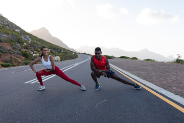 Fit african american couple in sportswear stretching on a coastal road