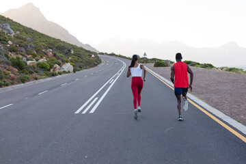 Fit african american couple in sportswear running on a coastal road