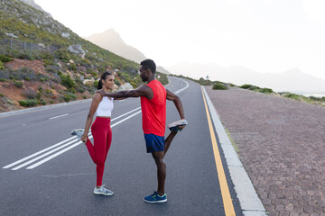 Fit african american couple in sportswear stretching on a coastal road