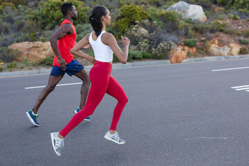 Fit african american couple in sportswear running on a coastal road
