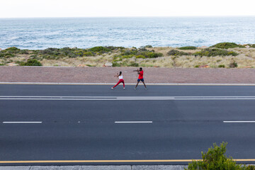 Fit african american couple in sportswear stretching on a coastal road