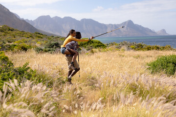 Fototapeta premium Fit african american couple playing with poles and embracing in mountain countryside