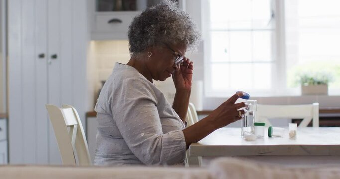Senior african american woman looking at empty medication container while sitting at home