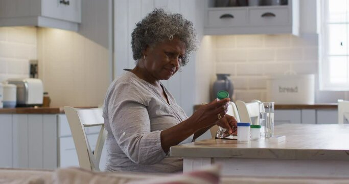 Senior african american woman looking at empty medication container while sitting at home