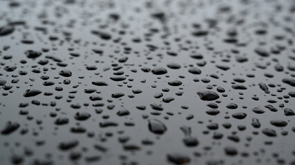 Fresh water drops on a black varnished or lacquered surface background