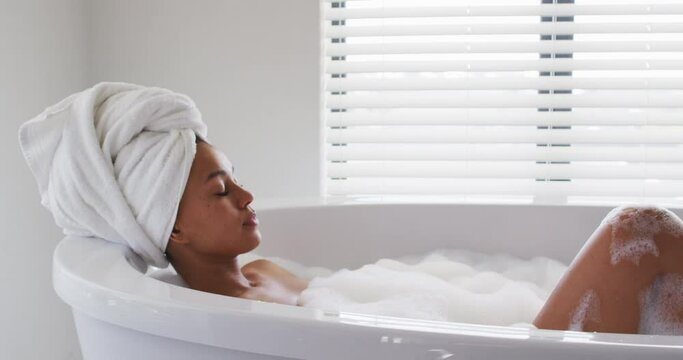 African american woman relaxing in the bath tub in the bathroom at home