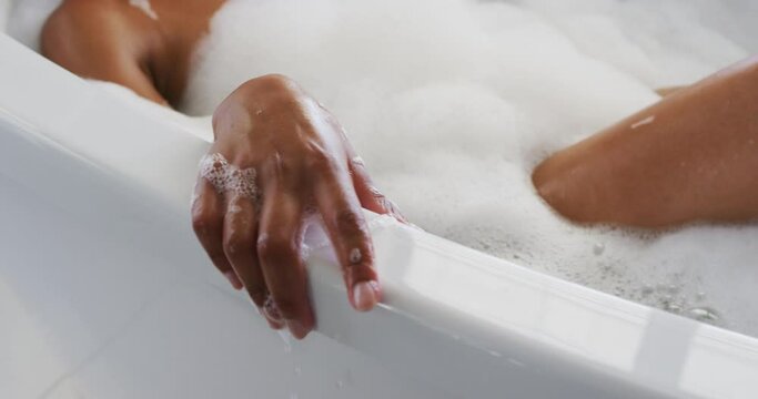 Close up of african american woman relaxing in the bath tub in the bathroom at home