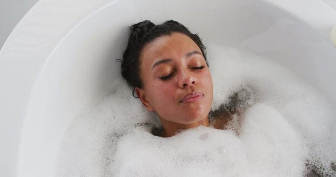 African american woman relaxing in the bath tub in the bathroom at home