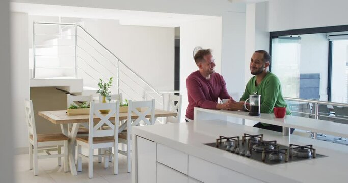 Multi ethnic gay male couple talking in kitchen