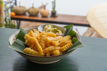 French fries on banana leaf and ceramic bowl with mayo sauce.