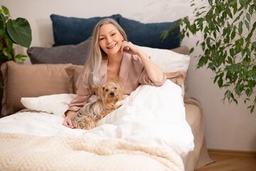 Grauhaarige blond weißhaarige silber liegt im Bett in Pyjama mit Hund morgen 