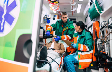 Two professional paramedics in an ambulance car with a patient on the stretcher