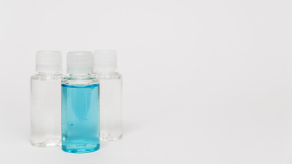 Alcohol sanitizing gel blue color and transparent in small bottles on the white background. Small bottles of shampoo and shower gel. Coronavirus personal protective equipment. PPE concept in 2021