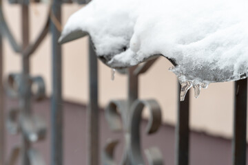 the facade of buildings after a snowfall is covered with snow and icicles. Parked cars are covered in snow and ice. Ice on roads and sidewalks. Danger of falling on slippery surfaces.