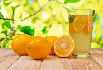 a glass of cold lemonade and fresh ripe citrus on a wooden table