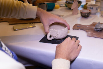man handles a clay bowl, in the workshop