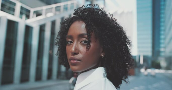 Close-up portrait of an attractive cheerful afro woman in a white shirt looking to the camera