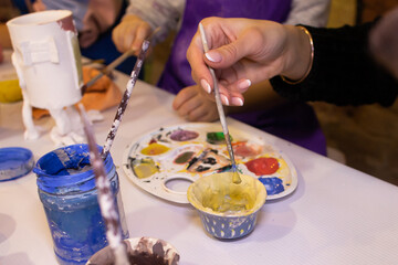 girl paints a clay product in the workshop