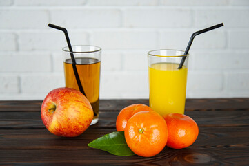 a glass of apple and orange juice with apples and oranges on the table