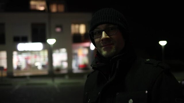 Junger Mann im Dunklen vor beleuchteten Geb&auml;ude