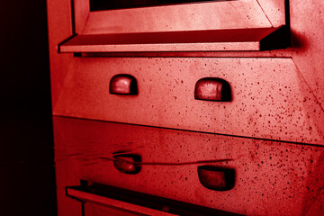 Detail of red aluminium bottom front window placed on glass with water on it on black background 