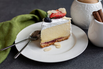 Cheesecake decorated with berries and almond flakes. A light and creamy dessert on white plate
