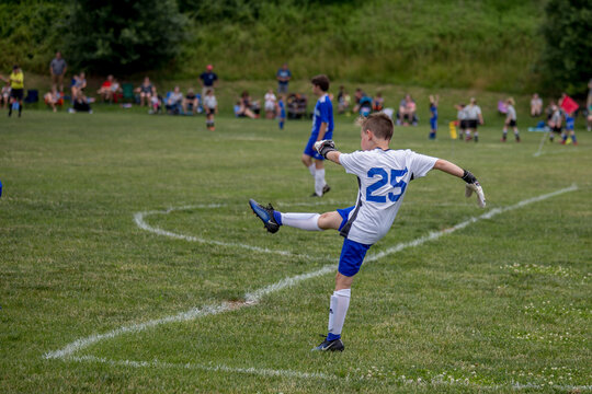 Young soccer goalie finishing his kick from the goal line. . 