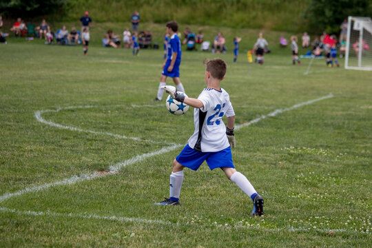 Young soccer goalie starting his kick from the goal line. . 