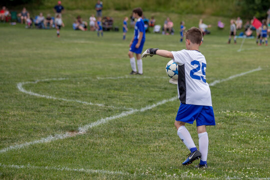 Young soccer goalie starting his kick from the goal line. . 