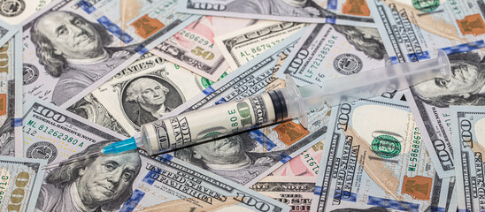 Syringe with 100 dollar banknote inside on dollar banknotes