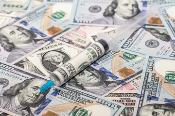 Syringe with 100 dollar banknote inside on dollar banknotes