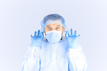 a man in a medical gown, mask and gloves straightens his hat