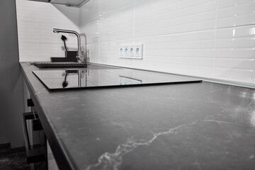 modern white kitchen with black countertop and induction touch plate. In the dim light