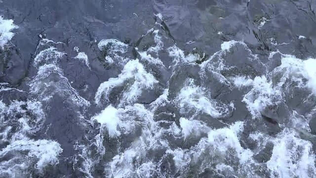 Turbulent gushing river water, vertiginous flow, swirling foamy water waves after heavy rain, turbid water rapids of Mur river, Austria
