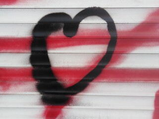 Heart in the graffiti style in black on a white wall and with red lines on the background