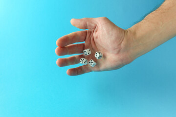 hand throws dice on blue background