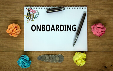 Onboarding symbol. White note with a word onboarding on beautiful wooden table, colored paper, paper clips, coins and calculator. Business and onboarding concept.