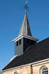 Tower with cross of the Reformed St John the Baptist church in the small village Exmorra in Súdwest-Fryslân in the province of Friesland, the Netherlands