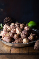 Jerusalem artichokes or topinambour, (topinambur), also known as earth apple or sunroot on wooden background.