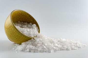 Sea salt in small porcelain bowl on white background