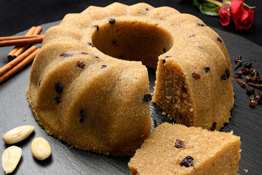 Homemade semolina halva with raisins served on black dish with nuts and cinnamon