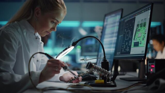 Modern Electronics Research and Development Facility: Beautiful Caucasian Female Engineer Does Computer Motherboard Soldering