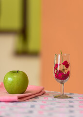Manzana verde con flores rojas en una copa