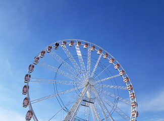 Top part of the ferris wheel in Krakow against a bright blue sky in the midday light. Horizontal photo.