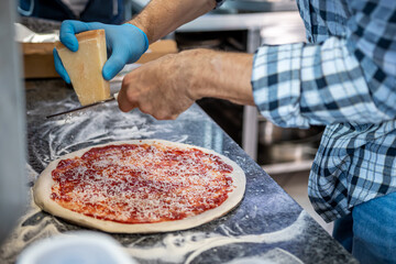 A man making a margherita pizza in a local pizza and gyros restaurant