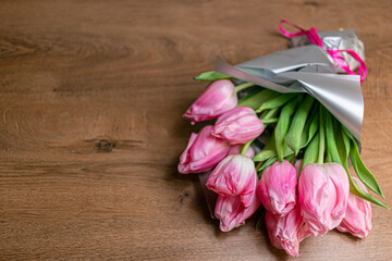 Bouquet of beautiful pink spring tulips in glass vase on wooden table near white brick wall. Concept of international women's day, mother's day, easter. Copy space. Valentine love day