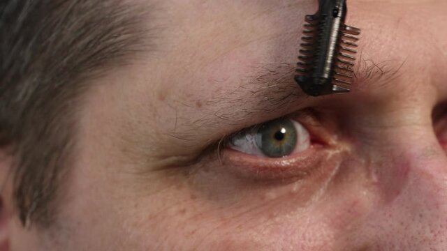 Trimming your eyebrow hair with a portable electric trimmer.