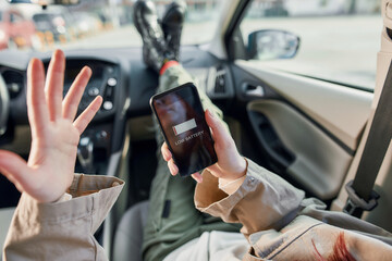 Close up of teenage girl holding smartphone in her hands, sitting in the car. Low battery notification on the screen. The concept of smartphone addiction