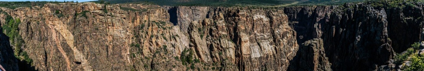 Fototapeta na wymiar Panorama shot of edge of rocky walls in black canyon of gunnison at sunny day in america