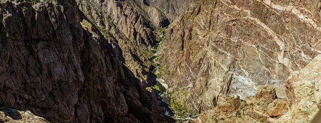 Panorama shot of gunnison river and rocky walls in black canyon of gunnison at sunny day in america